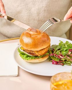 Grilled chicken burger with lettuce and sauce served with a side salad on a white plate at Mademoiselle Angelina tea room.