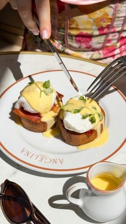 Two eggs Benedict with hollandaise sauce on a plate at Angelina Paris - Domaine de Trianon tea room.