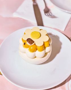 Pâtisserie délicate avec crème et décor en forme de fleur sur assiette blanche dans un salon de thé.