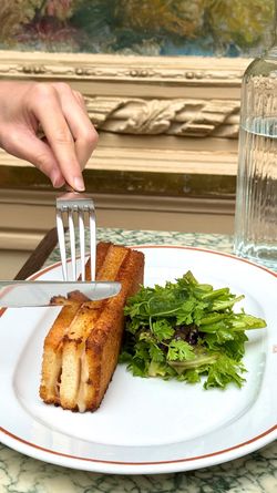 Fried sandwich with salad greens on a white plate with orange rim at Angelina Paris - Rivoli
