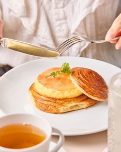 Pastry from Mademoiselle Angelina tea room served with a cup of tea, photographed with a person using fork and knife.