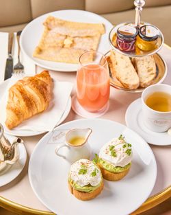 Breakfast spread with croissant, crepe, avocado eggs, juice, tea, bread, and jam at Mademoiselle Angelina tea room.
