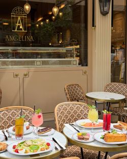 Terrasse de la pâtisserie Angelina Paris - Rivoli avec tables, chaises et diverses boissons et desserts sur les tables.