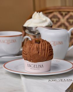 Mont-Blanc pastry served on a white plate with Angelina Paris branding, accompanied by a teapot, cup, and whipped cream bowl.