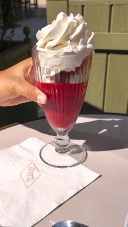 Verre élégant contenant un dessert rouge avec une généreuse couche de crème fouettée au Salon de thé Mademoiselle Angelina