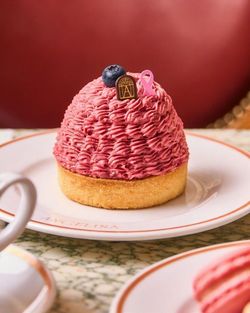 Pâtisserie du Boutique Angelina Paris avec une gourmandise montée en dôme rose décorée d'un chocolat et myrtille.