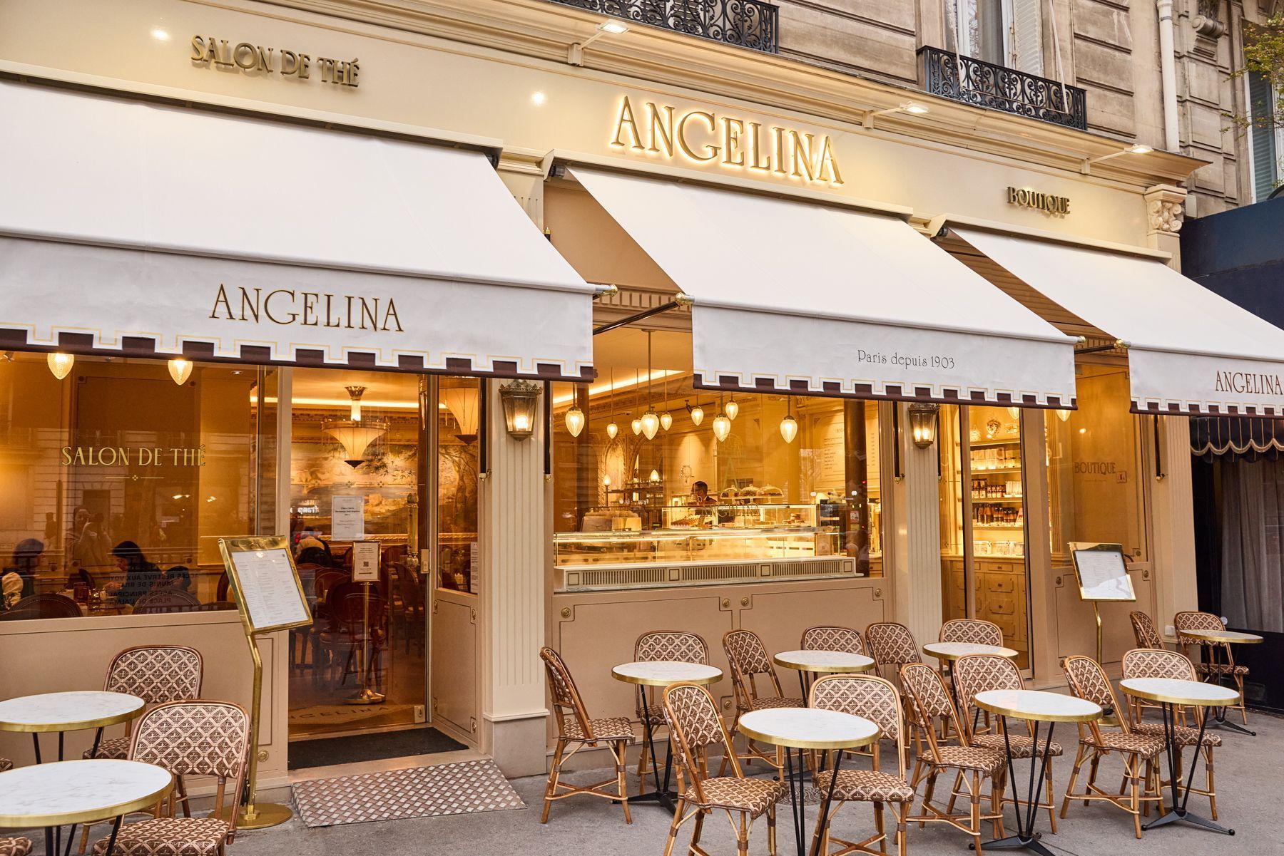 Elegant tea room with outdoor seating, classic Parisian style, and warm lighting at Angelina Paris – Alma, Salon de thé.