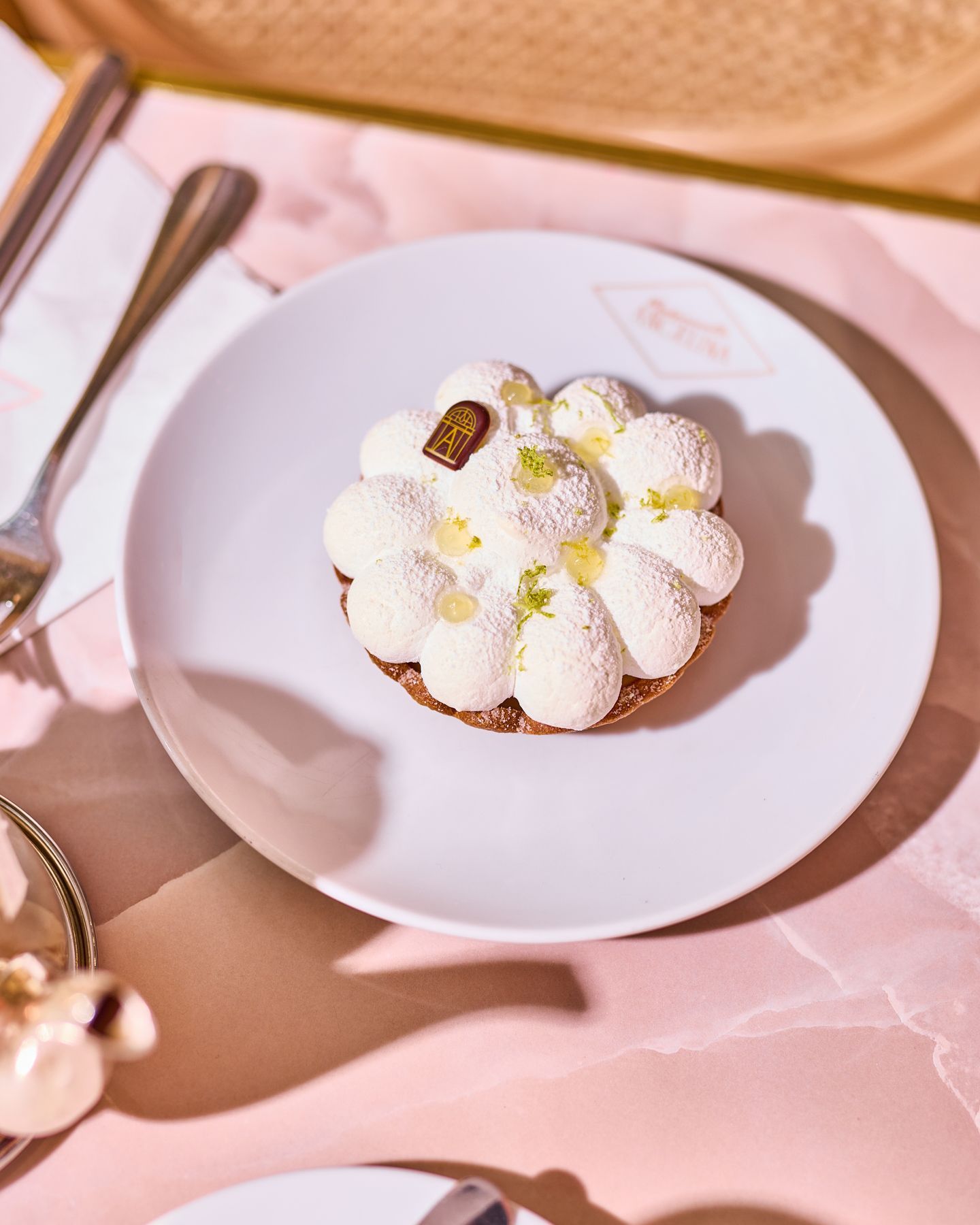 Tartelette pâtissière décorée de crème et de poudre blanche servie sur une assiette blanche dans un salon de thé.