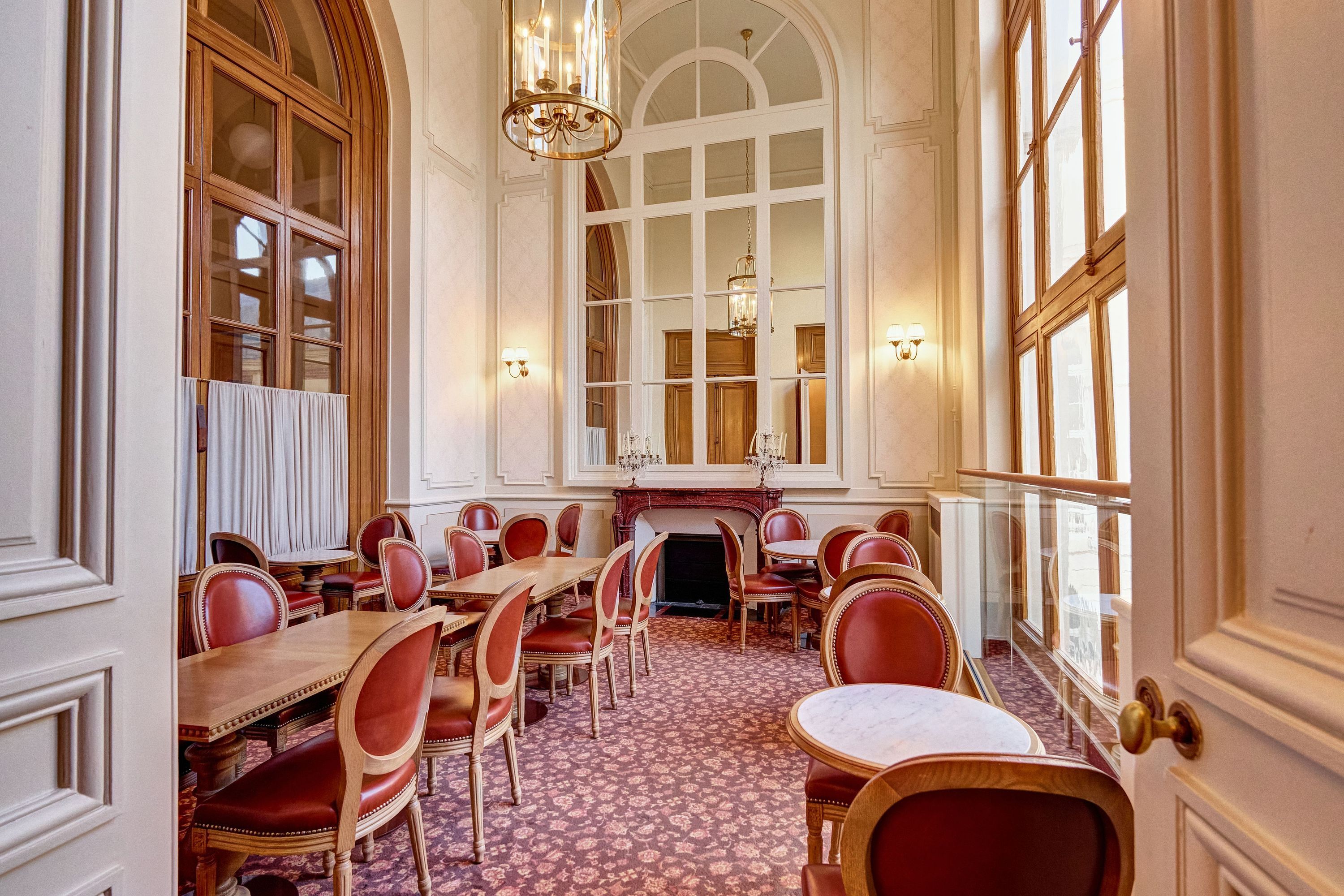 Elegant tea room in Angelina Paris at Château de Versailles, featuring classic wooden chairs and large windows.