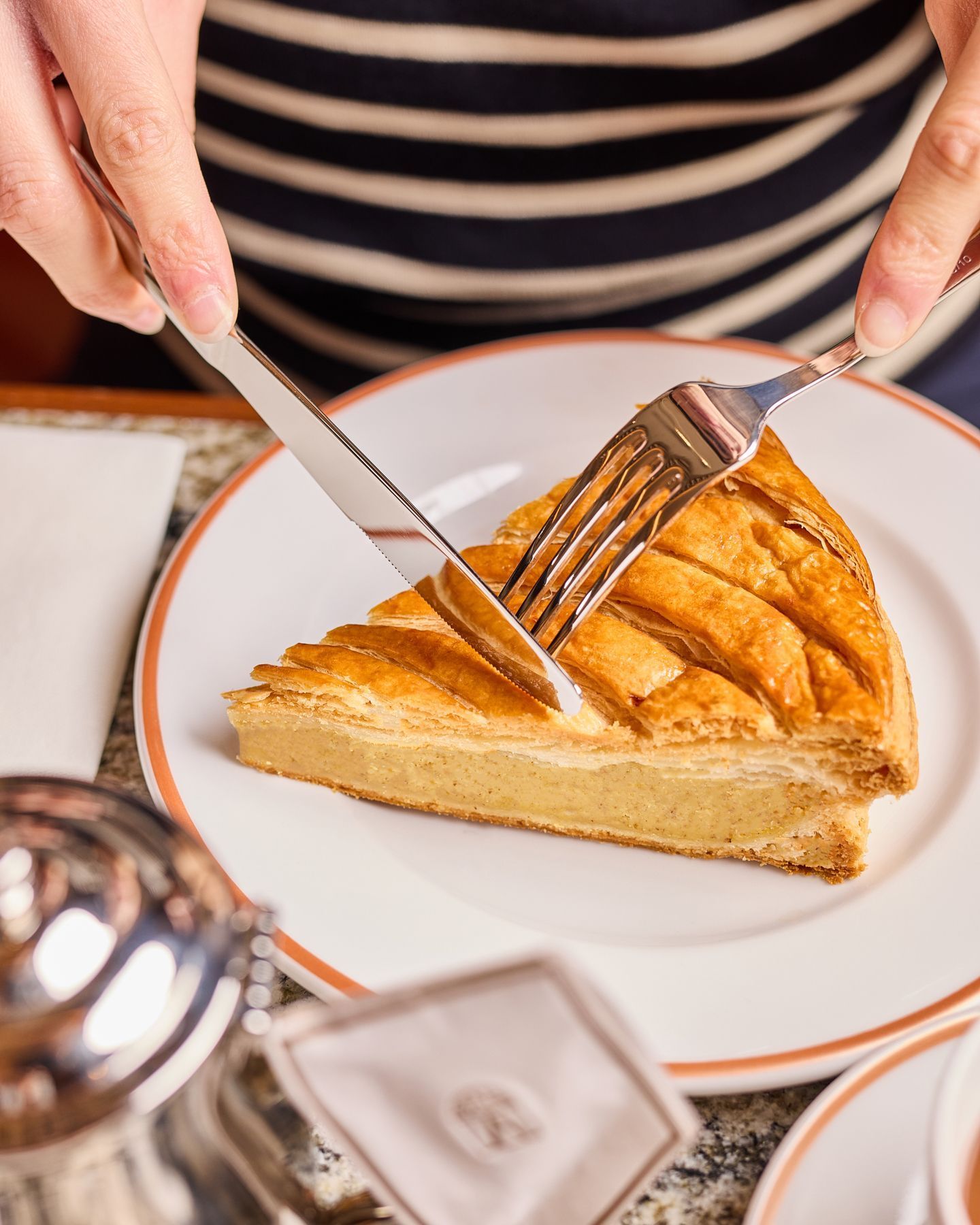 Part de tarte traditionnelle servie dans le salon de thé Angelina Paris, décor typique avec assiette blanche et bord orange.