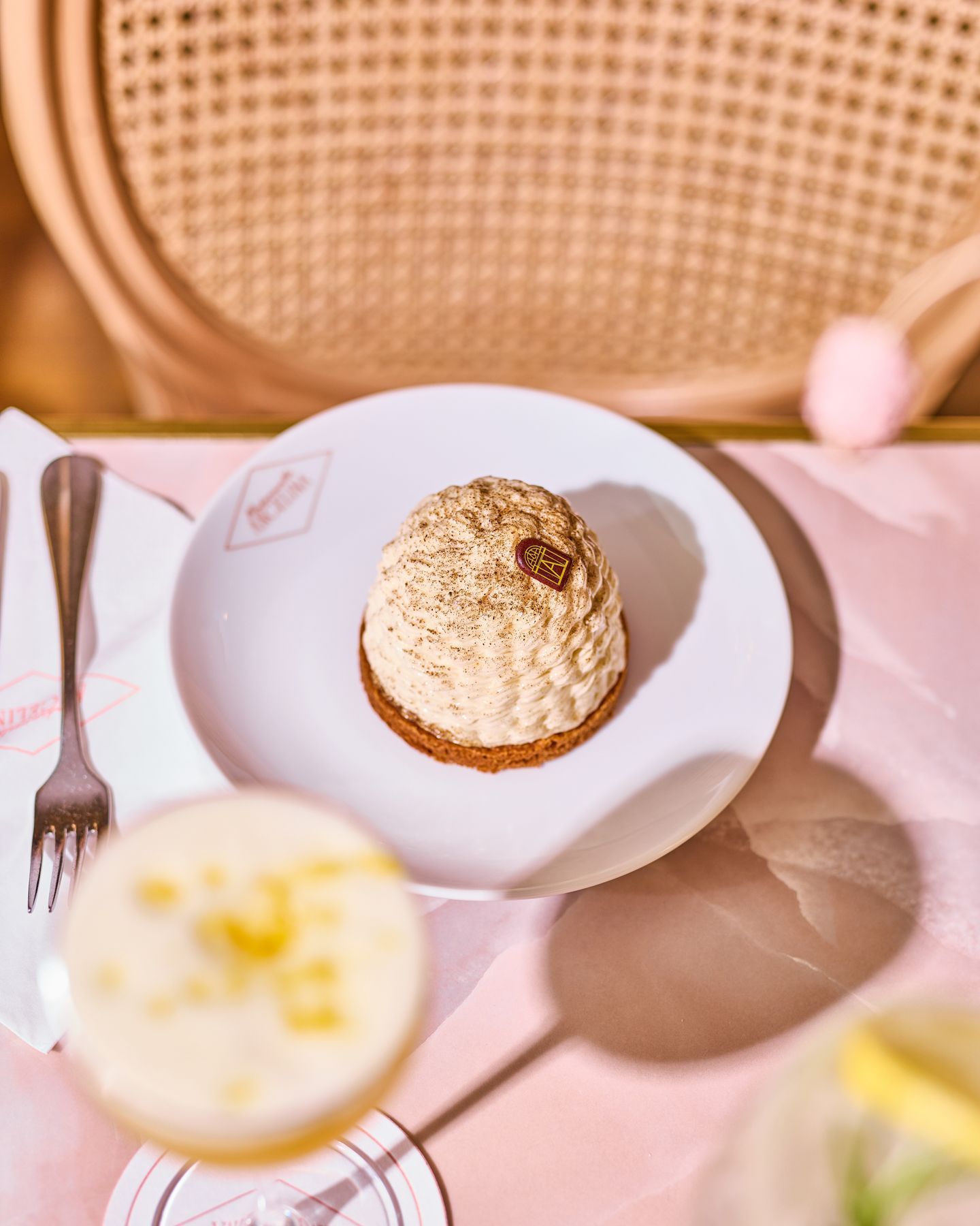 Pastry from Mademoiselle Angelina tea room on white plate with pink tablecloth and rattan chair in the background.